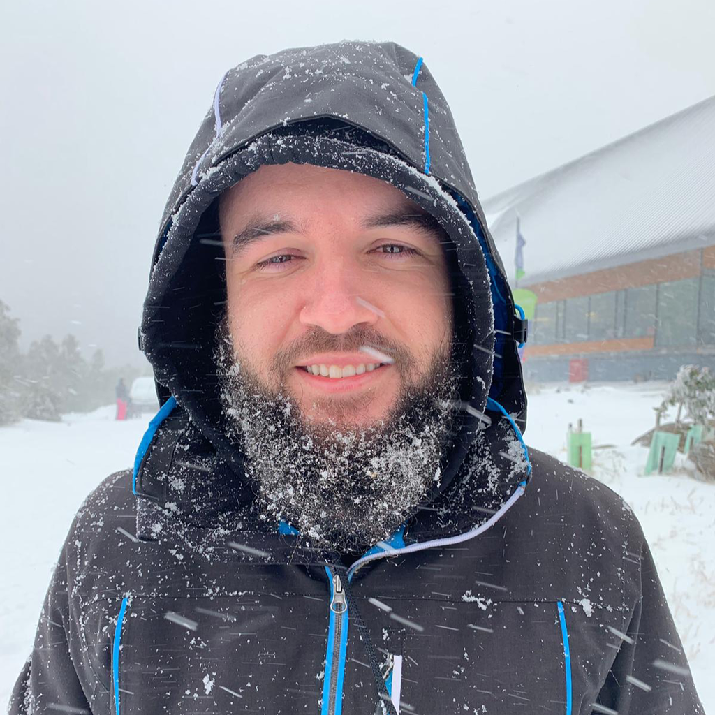 Caio sorrindo na neve, usando uma jaqueta de inverno